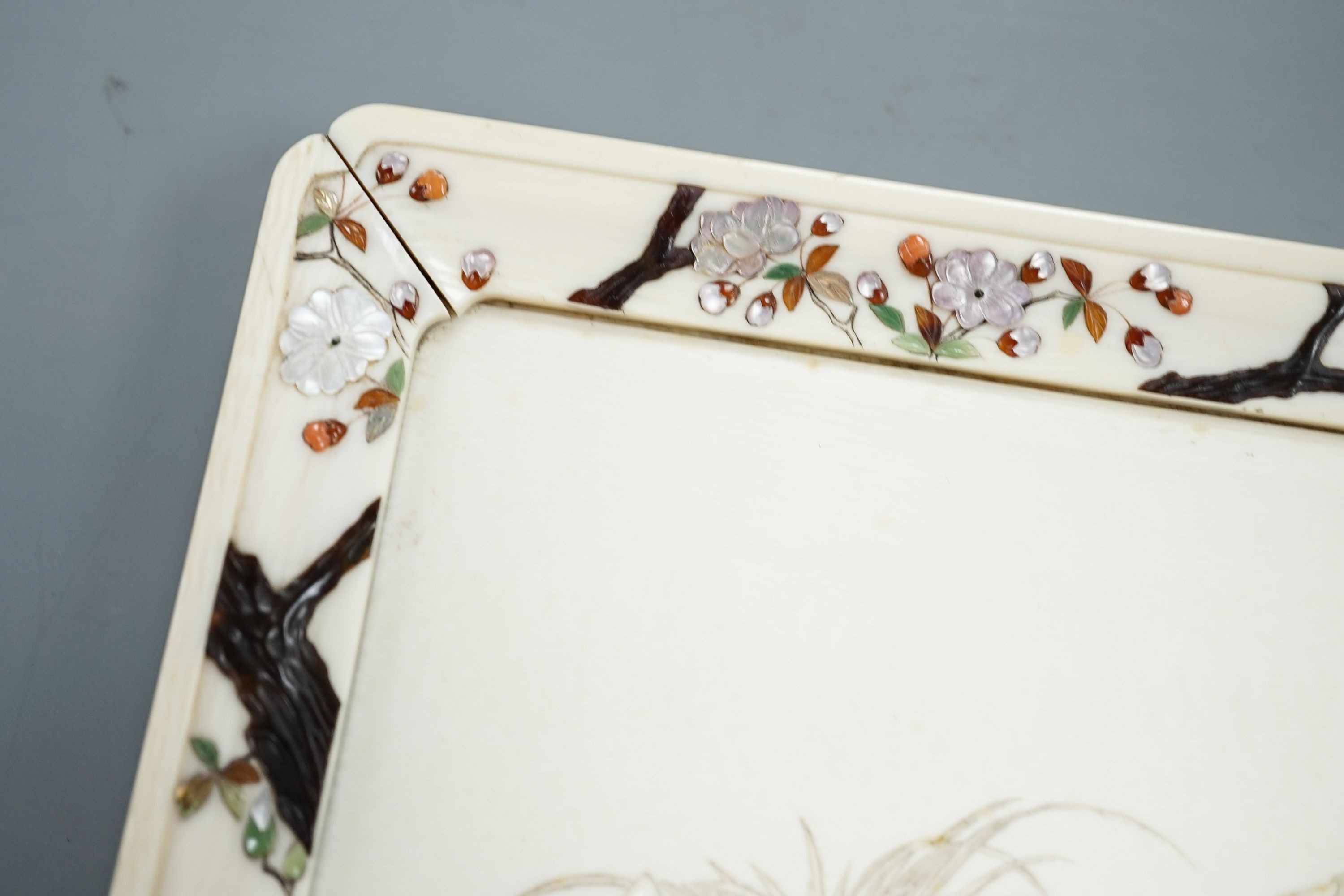A Japanese ivory tray/plaque, Meiji period, with sunk-in carving of boy with dove, the surround decorated with Shibayama inlaid flowers etc. 15 x 20cm